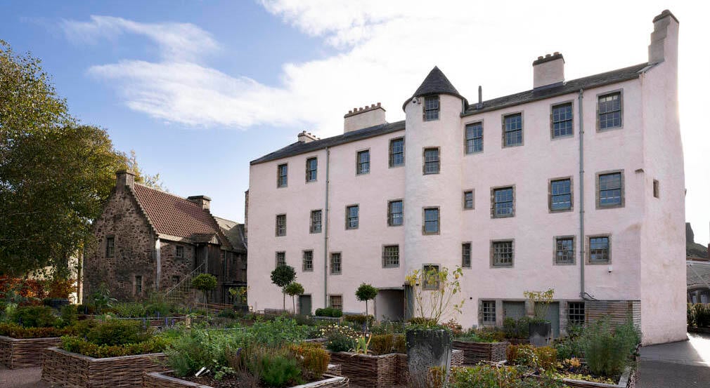 The new gardens at the back of the Abbey Strand buildings. The back of a cream building with a garden in the back. The garden is made of of a serious and raised beds of plants.