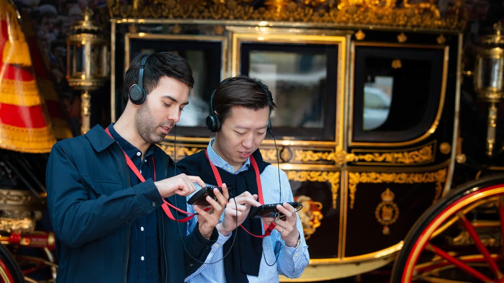 Visiting the Royal Mews, Buckingham Palace Two people look at multimedia guides in front of carriage