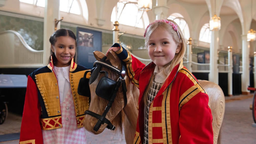 Children with wooden horse Children tacking up wooden horse