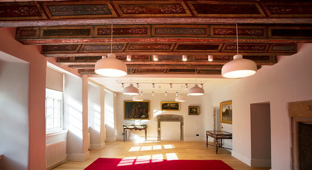 The Midhope Room inside the Learning Centre. The interior of a room with old wooden beams, white walls and paintings on the wall.