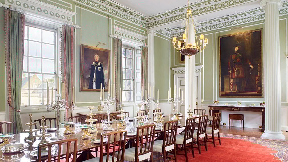 The Royal Dining Room A lavish dining room with the table laid and decorated. The room is filled with paintings and a chandelier.