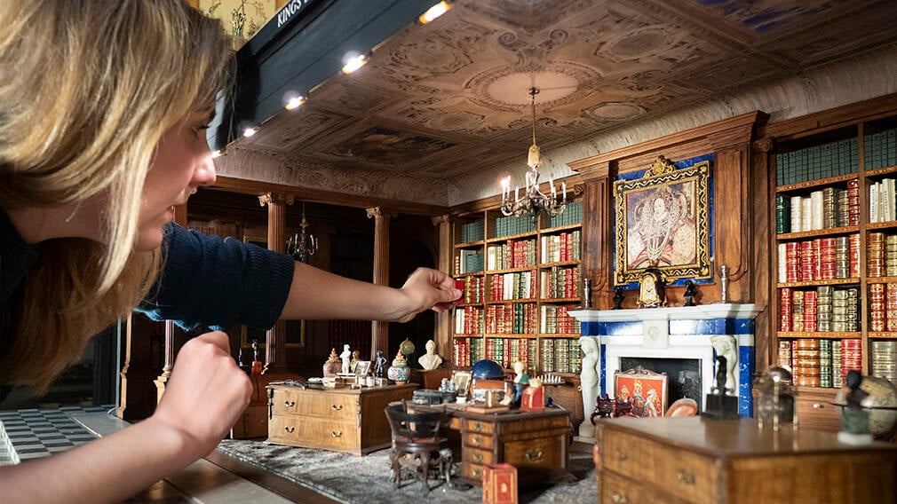 Curator with Queen Mary's Dolls' House A curator places a miniature book in the Queen Mary's Dolls' House miniature library