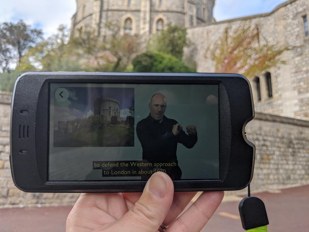 The BSL multimedia tour A hand holding a multimedia device, like a mobile phone, in front of the Round Tower