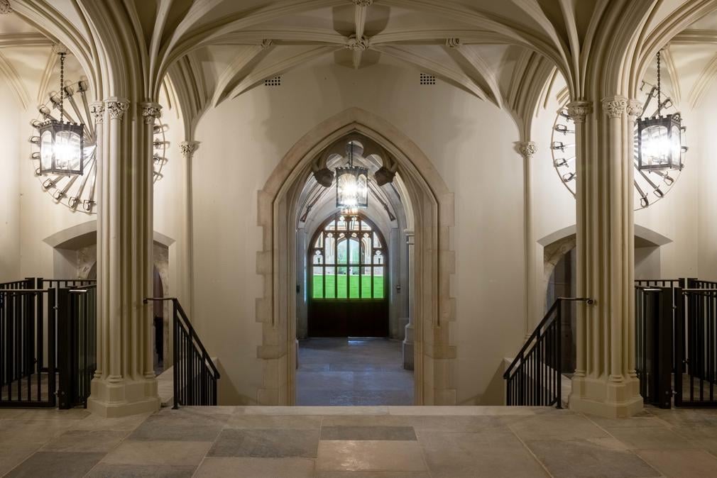 The view down to the State Entrance from the Inner Hall Image shows the Inner Hall of Windsor Catle. A large open space with stone columns.